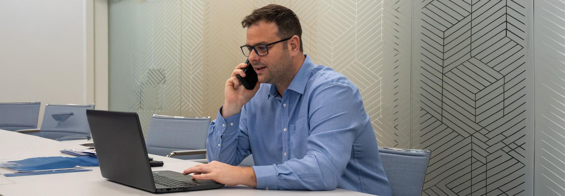 Hutchings Pharmacy consultant taking a phone call at his laptop